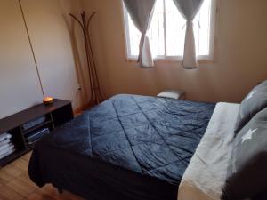 a bedroom with a bed with a blue blanket and a window at Portal del Sol in Villa Yacanto +13 photos