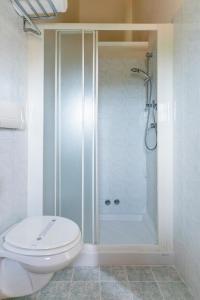 a white bathroom with a shower and a toilet at Hotel Corallo in Castiglioncello