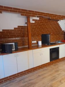 a kitchen with white cabinets and a brick wall at Garsoniera Sic Zona Terapia Zona linistita la casa cu parcare in Cluj-Napoca