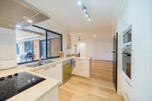 a kitchen with white cabinets and a large window at Springfield Breeze - Newly furnished home, Sunny Patio and BBQ in Goodna