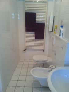 a white bathroom with a toilet and a sink at Hotel zur Sportsbar in Horn-Bad Meinberg