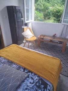a bed in a room with a chair and a window at Bungalow Hibiscus Monique &Frédé in Le François