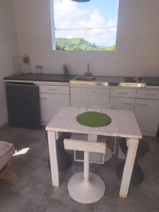 a white kitchen with a table and a window at Bungalow Hibiscus Monique &Frédé in Le François