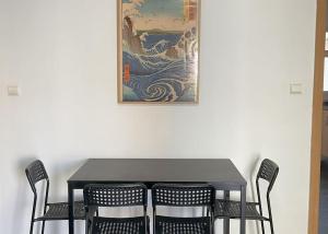 a table with four chairs and a painting on the wall at Disfruta frente al mar, a 50 metros, y desconecta in Torre de la Horadada
