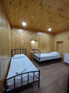 deux lits dans une chambre aux murs en bois dans l'établissement Kazbek wiev Hostel, à Kazbegi