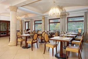 a restaurant with wooden tables and chairs and windows at Retro Riverside Wellness Resort in Karlovy Vary