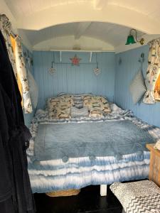 a bedroom with a bed in a blue room at The Hen House Shepherds hut with hot tub in Chittoe