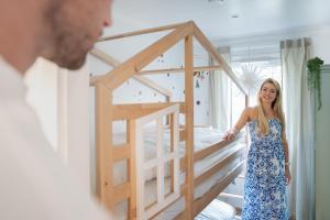 a woman in a dress standing next to a bed at Ferienhaus Landliebe Lodges in Falkenthal