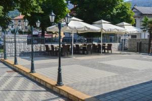 a patio with tables and white umbrellas and tables and chairs at Gostinstvo Tomex in Ilirska Bistrica
