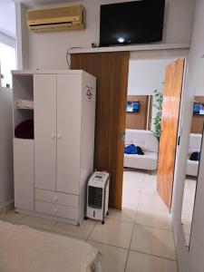 モンテス・クラロスにあるkitnet 103 com ar e 2 tv smartのリビングルーム(白い冷蔵庫、テレビ付)