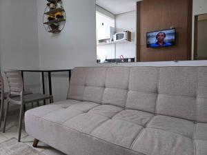a couch in a living room with a table and a tv at kitnet 103 com ar e 2 tv smart in Montes Claros