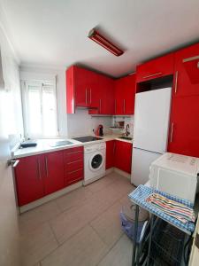 una cucina con armadi rossi e frigorifero bianco di Apartamento Lola2 a Nerja