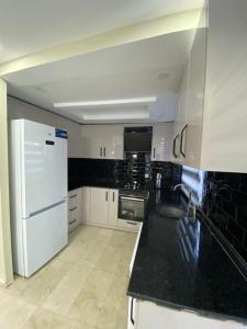 a kitchen with a white refrigerator and a black counter top at Happy Land Belek in Belek