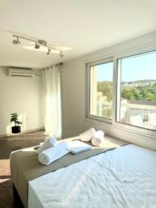 a bedroom with a bed with towels and a large window at GRACE Apartment Next to the Akropolis in Athens