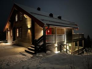 eine Blockhütte im Schnee bei Nacht in der Unterkunft Alpstigen 10B - Newly built sports cottage with lovely views (lower apt) in Järvsö