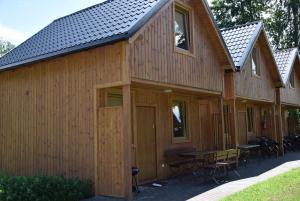 a large wooden building with a table and chairs at Domki pod lasem Sobieszewo in Gdańsk