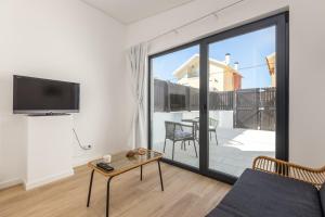 a living room with a couch and a tv on a wall at Casa das Camarinhas in Aveiro