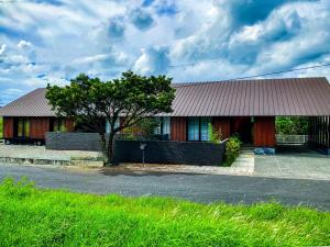 a building with a tree in front of it at 奄美大島の宿 in Tatsugo
