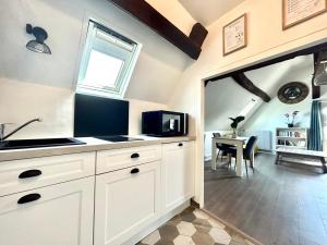 a kitchen with white cabinets and a window and a table at L Écuyer appartement au cœur du quartier historique in Chartres