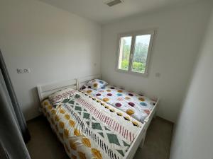 a small bedroom with a bed with a comforter and a window at La Gourgotte in Ajac