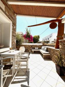a patio with white tables and chairs and a brick wall at Aegeo Inn in Antiparos