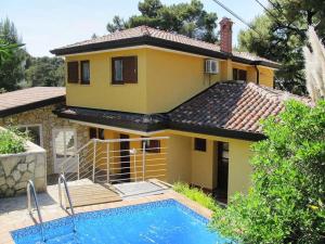 a yellow house with a swimming pool in front of it at Holiday Home Yellowhouse in Kaštel