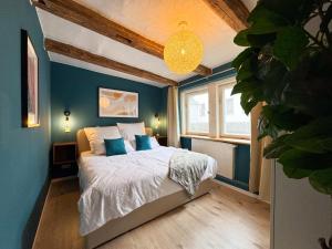 une chambre avec des murs bleus et un lit avec des oreillers bleus dans l'établissement Haus Ludwig - Saniertes Fachwerkhaus im Harz - 12 Personen, à Thale