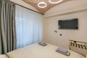 a bedroom with a bed and a tv and a window at Biagio Boutique Studio - in Old Town - Ultra Central in Braşov