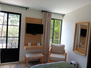 a room with a bed and a chair and a television at Quinta Mercedes in Guanajuato