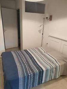 a bed with a striped blanket on it in a room at Joli studio décoré proximité cure centre ville in Rochefort