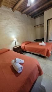 two beds in a room with red sheets and towels at La huella Jáchal - Casas de Campo in San José de Jáchal