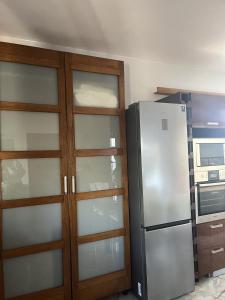 a kitchen with a refrigerator and some glass cabinets at Apartament ZIELONY TARAS in Kielce