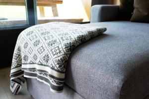 a blanket is sitting on the end of a bed at Lys og moderne leilighet rett ved skiløypa på Nordseter - Kort vei til Sjusjøen, Lillehammer og Hafjell - Dyr ikke tillatt in Nordseter