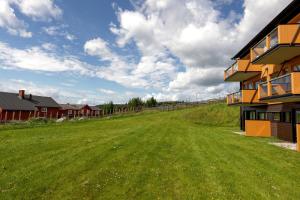 a green field next to a building with a house at Lys og moderne leilighet rett ved skiløypa på Nordseter - Kort vei til Sjusjøen, Lillehammer og Hafjell - Dyr ikke tillatt in Nordseter