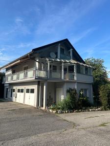 a white house with a balcony and a driveway at Ferienwohnung Waldblick, Faaker See in Oberaichwald