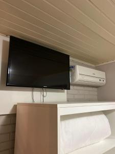a flat screen tv on a shelf with a printer at Pousada dos Pássaros in Gramado