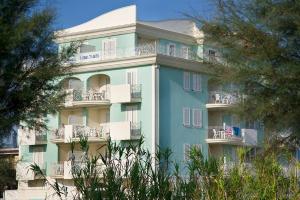 馬帝斯茲羅的住宿－布魯馬爾公寓，一座蓝色的大建筑,设有白色的阳台和树木