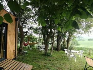 a group of chairs and tables in a yard with trees at Évasion nature - Tiny house in Baziège