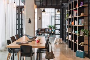 a room with a table and chairs and a book shelf at Moxy Katowice Airport in Pyrzowice