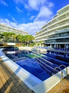 a large swimming pool in front of a building at Seafront apartment in Blanes S'Abanell Central Park in Blanes