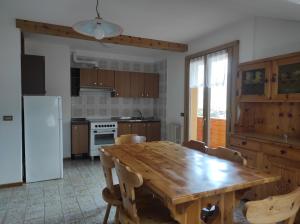 a kitchen with a wooden table with chairs and a refrigerator at Baita de Ciano in Valdidentro
