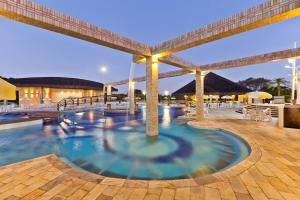ein Pool in einem Resort mit Tischen und Sonnenschirmen in der Unterkunft Aguativa Golf Resort in Cornélio Procópio