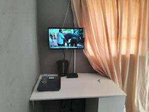 a television sitting on top of a desk next to a curtain at Letz Guest Lodge in Tolwe