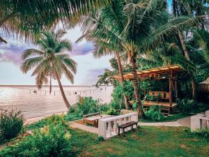 a bench sitting next to a beach with palm trees at Beachfront Private Bungalow in Libertad