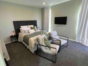 a bedroom with a large bed and a chair at Cozy Lakeside Oasis in Rotorua