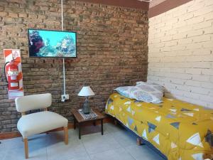 a bedroom with a bed and a chair and a brick wall at Alojamiento Práctico y acogedor in Zapala