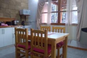 a kitchen with a wooden table and four chairs at Alojamiento Práctico y acogedor in Zapala