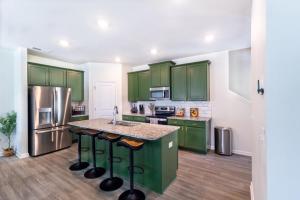 a kitchen with green cabinets and a stainless steel refrigerator at GoodLiving Atlanta - Family Getaway - Pets Welcome in Atlanta