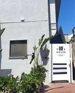 een wit huis met een bordje waarop 'life house' staat bij Life House B&B in Follonica