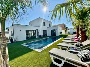 a row of chaise lounges next to a swimming pool at Villa Vanille Cap d Agde Luxe piscine chauffée 5 étoiles in Le Grau-dʼAgde
